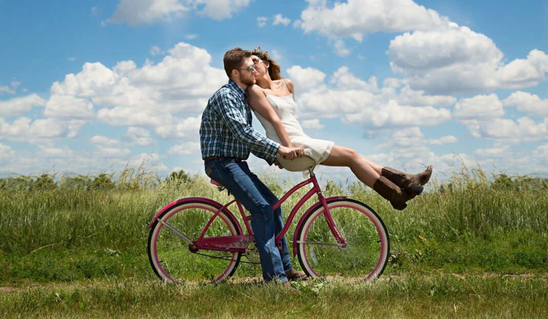 Young couple in honeymoon phase, riding a bicycle